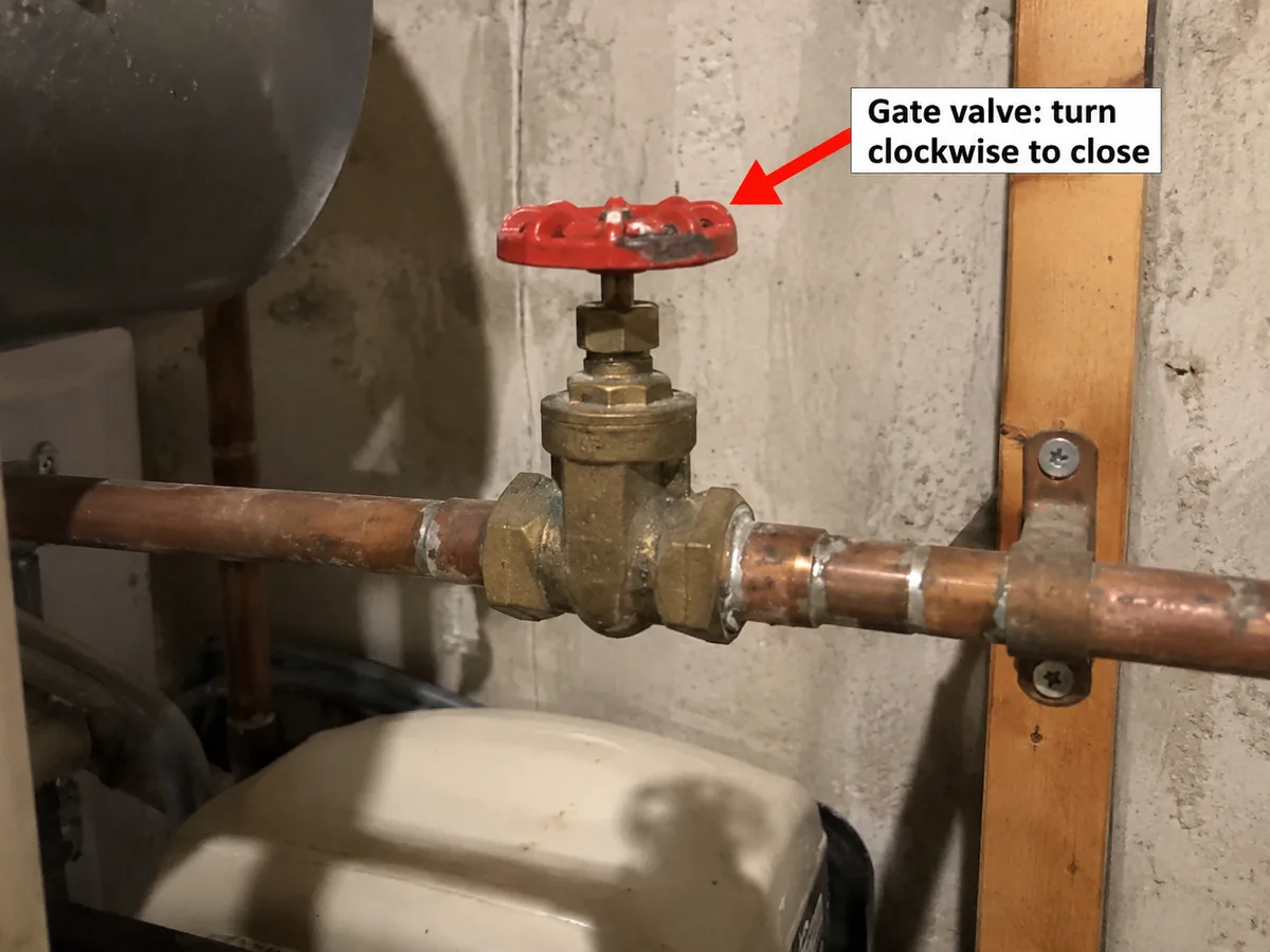 Brass gate valve with a red round wheel handle on a copper pipe