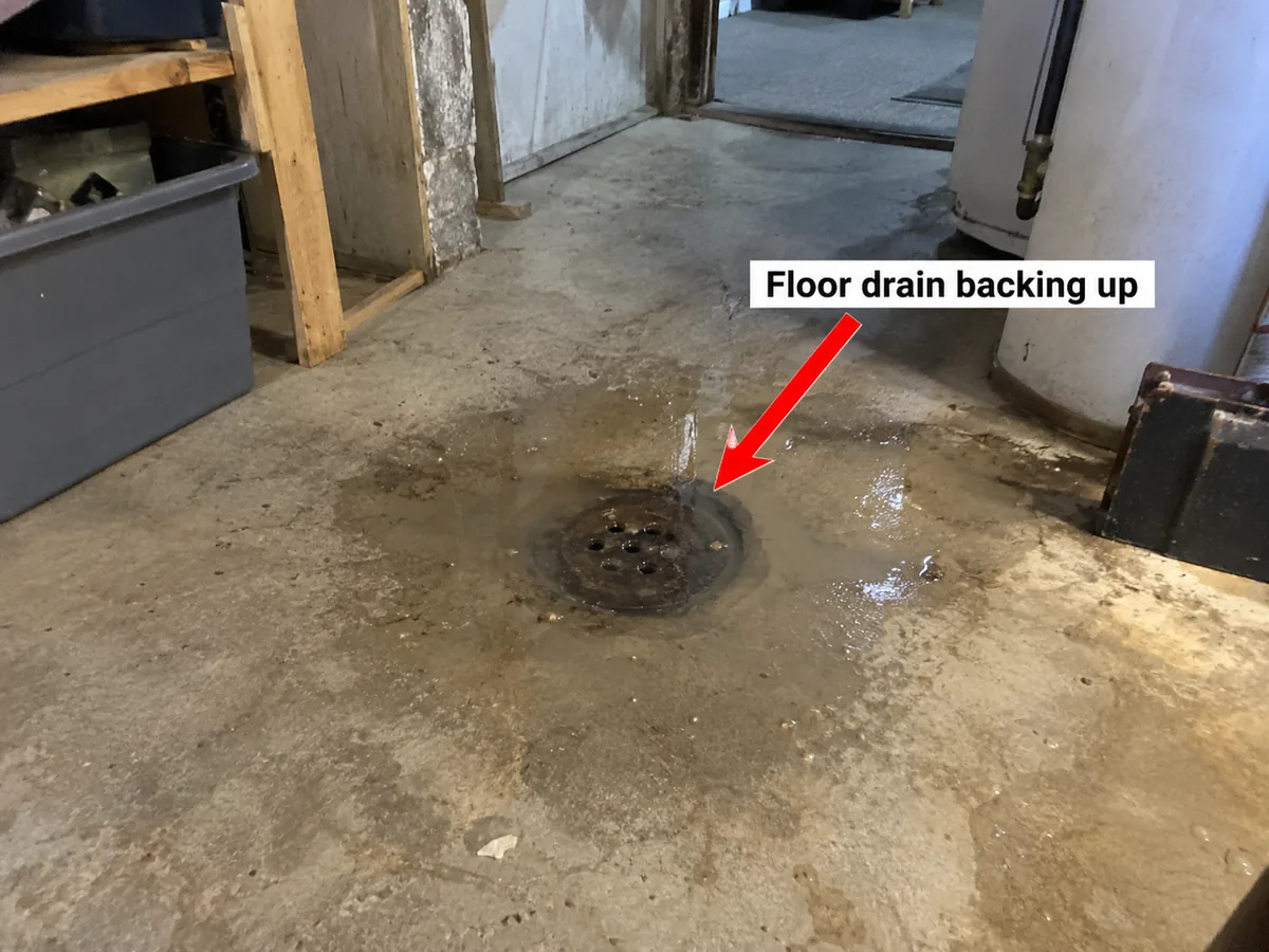 Cast iron floor drain in a basement with water pooling around it